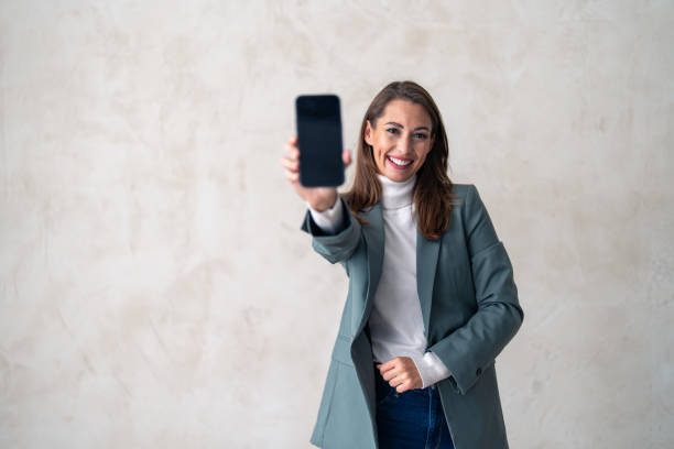 Studio portrait of businesswoman with phone for product placement Studio portrait of businesswoman with phone for product placement, branding and mobile app advertising, marketing mockup, online corporate info, web notification. spokesmodel stock pictures, royalty-free photos & images