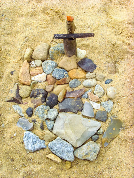 小石で作られたビーチの砂に十字架のある小さな墓。 - osterholz ストックフォトと画像