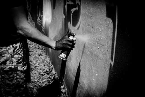 One male, male artist painting a graffiti on the wall on building top.