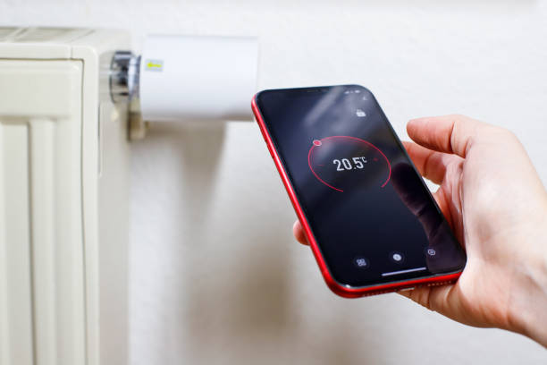 istock Controlling radiator heating temperature with a smart phone, close-up with radiator on the background. Concept of a smart home and mobile application for managing smart devices at home 1973357531