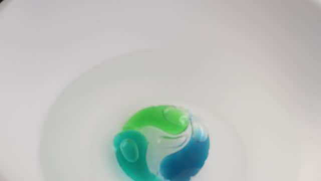 Washing gel capsule pod with laundry detergent to throw into the water. Full frame shots of blue-green liquid laundry detergent pods.