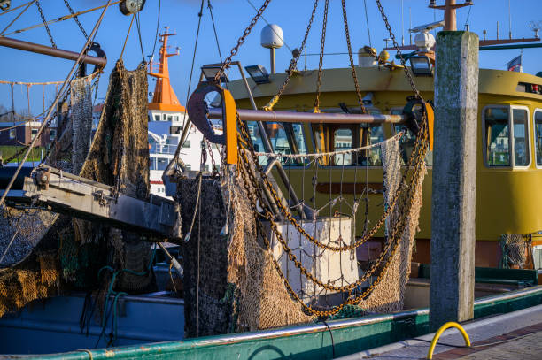 Drag net on a moored wadden sea crab or shrimp fishing boat with rusty iron chains