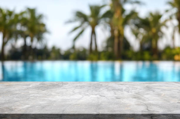 istock Table or surface with tropical swimming pool or beach in the background 1973399618