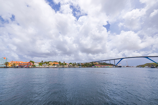 Beautiful view of Willemstad with the high Connexion Bridge over Saint Anna Bay against a blue sky with fluffy white clouds. Curacao.