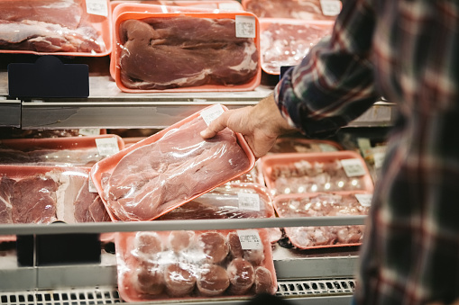 Close-up of unrecognizable woman choosing some fresh meat at local supermarket