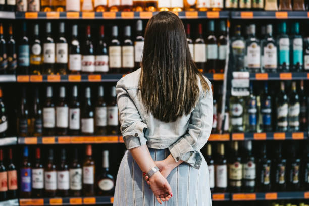cliente de mujer mirando un estante de vino en el supermercado - vertical wine bottle variation rack fotografías e imágenes de stock