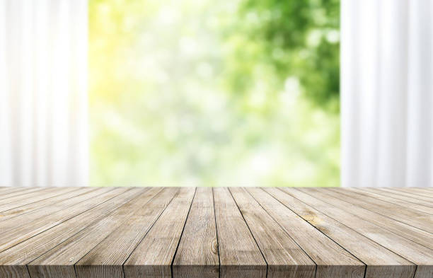 istock Wooden table on window background with garden and trees 1973420684