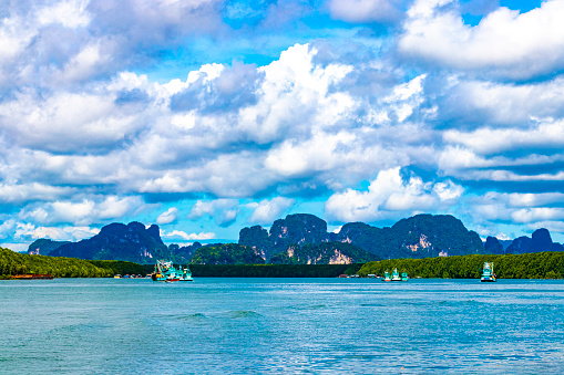 Beautiful tropical paradise panorama view on turquoise water beach and between limestone rocks hills cliffs mountains and Thai fisherboats on Ao Nang Beach in Amphoe Mueang Krabi Thailand in Southeast Asia.