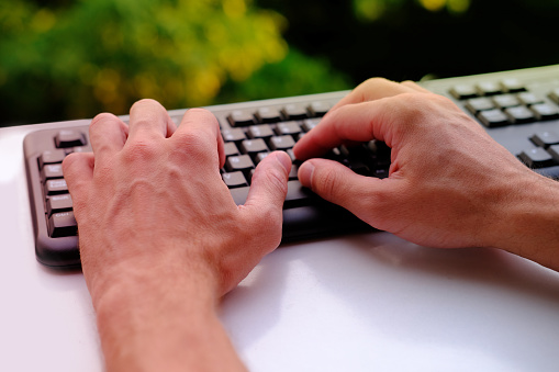 close-up male hands typing text on black keyboard, online learning, office environment, computer peripherals, digital work routine