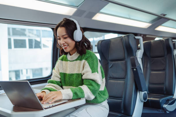 young asian woman working on a laptop in train - high speed train audio стоковые фото и изображения