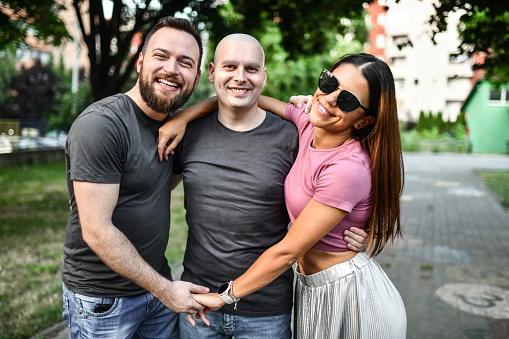 Male And Female Friends Embracing Male Friend After He Beats Cancer