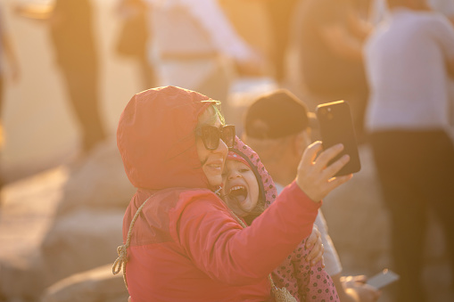 Photo of mother and 5 years old daughter taking selfie photo with smart phone on Nemrud Dagh, Adiyaman, Turkey. Shot with a full frame mirrorless camera.