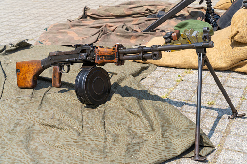 A close up on a machine gun replica from World War I seen next to some sandbags and ammo crates spotted next to a camp seen on a cloudy summer day during a historic reenactment in Poland