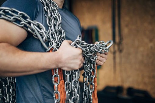 One man, fit male carrying chains in gym.