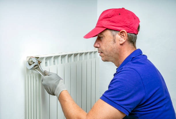 istock Plumber fixing and bleeding a heating radiator. 1973564401