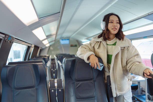 азиатская молодая женщина ждет следующей остановки поезда - high speed train audio стоковые фото и изображения