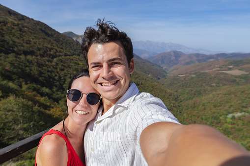 Young latin couple taking selfie at mountain peak. Tourism, nature and active lifestyle concepts. High quality photo