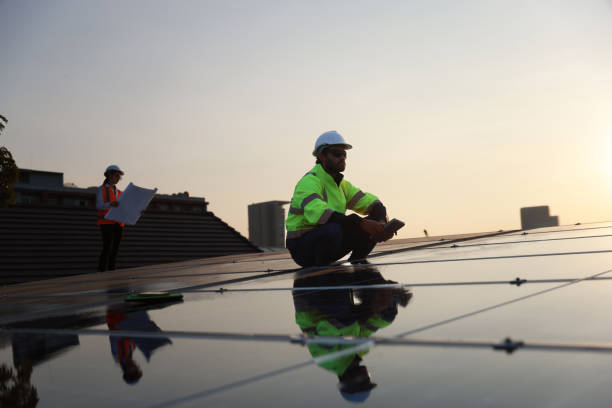 istock smart site solar engineer with a green safety jacket working on a solar rooftop, Specialist technician professional engineer with laptop and tablet maintenance checking to install solar roof panel on the factory rooftop under sunlight. 1973643862