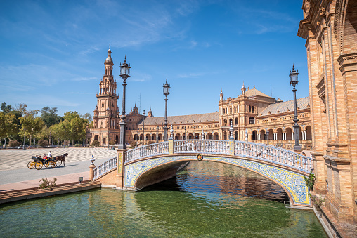 Sunny day in Plaza de Espana in Seville, with a horse carriage in front of the canal. Andalusia (Seville, Andalucia)