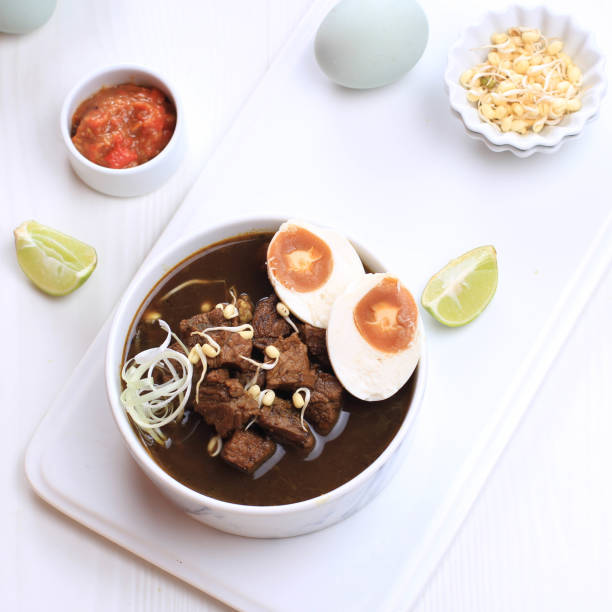 istock Rawon, Indonesian Traditional Beff Black Soup from East Java. Served on a Bowl wth Shrimp Cracker (kerupuk Udang) and Chilli Paste and Salted Egg 1973755917