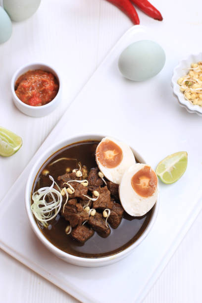 istock Rawon, Indonesian Traditional Beff Black Soup from East Java. Served on a Bowl wth Shrimp Cracker (kerupuk Udang) and Chilli Paste and Salted Egg 1973755918