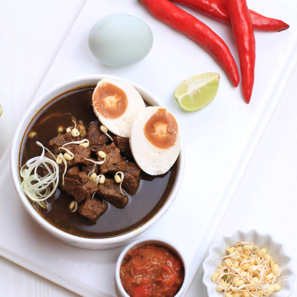 istock Rawon, Indonesian Traditional Beff Black Soup from East Java. Served on a Bowl wth Shrimp Cracker (kerupuk Udang) and Chilli Paste and Salted Egg 1973756142