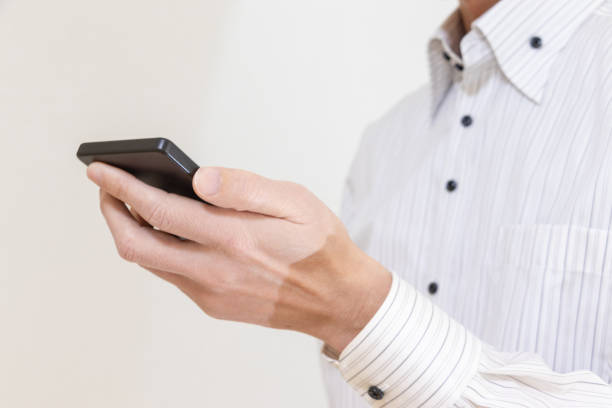 istock A man in a white shirt holding a smartphone in one hand 1973759524