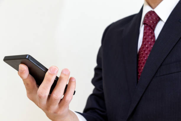 A man in a suit holding a smartphone in one hand