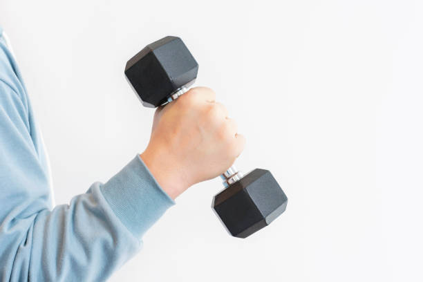 istock Male hand holding an iron black dumbbell on white background, copy space. 1973774538