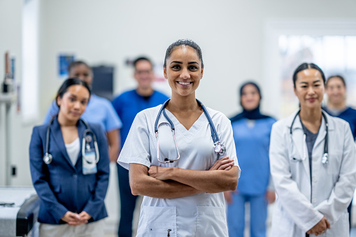 A small team of Medical Professionals stand together as they pose for a portrait.  They are each dressed professionally and are smiling.