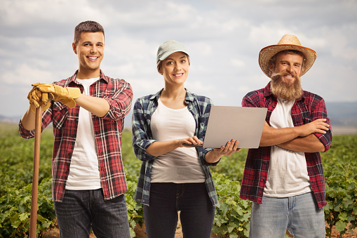 Group of farmers standing on a vineyard with a laptop computer, new agriculture technology in modern farming