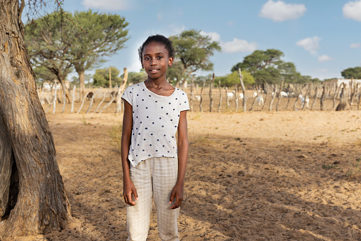 village , african girl at the farm, kraal with goats in the background, Kalahari small livestock