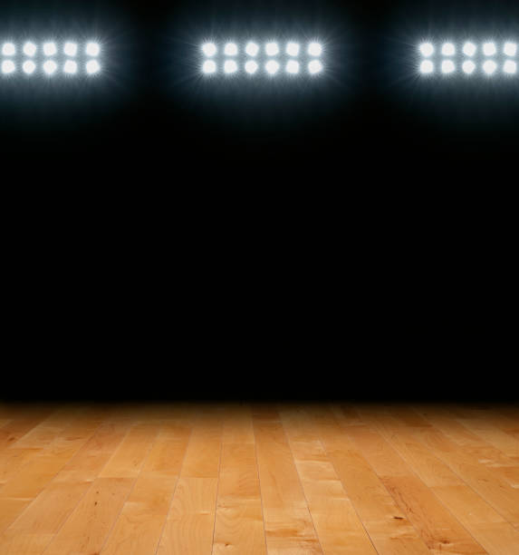 istock Maple basketball floor with dark background below arena lights 1973927615