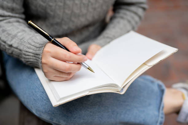 istock A woman keeping her diary or writing something in her notebook while sitting outdoors. 1973998421