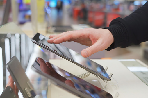 A white man uses a digital tablet in an electronics store.