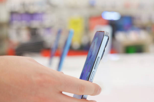 Hand of male buyer testing smartphone in electronics store