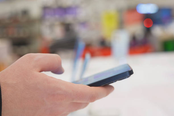 Hand of male buyer testing smartphone in electronics store