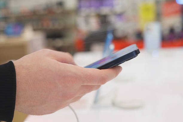istock Hand of male buyer testing smartphone in electronics store 1974018813