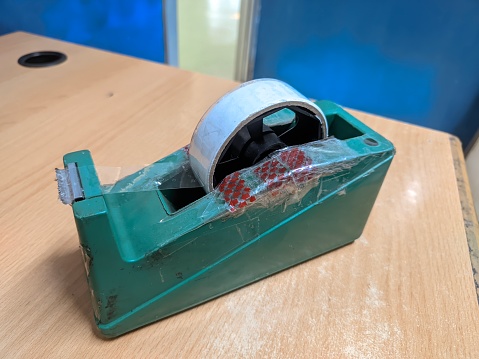 Green tape dispenser on a wooden table