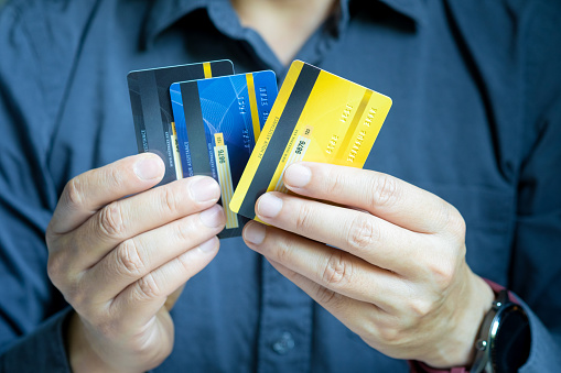 Man holding several credit cards and he is choosing a credit card to pay and spend Payment for goods via credit card. Finance and banking concept