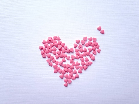 Adorable heart made of pink sugar sprinkles on a light background close-up