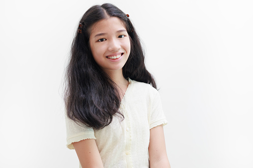 Portrait of a pretty and attractive little Asian girl is captured looking at the camera with a bright expression and a charming smile, set against a white background.
