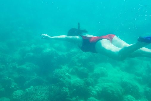 Beautiful women snorkeling in the tropical sea. Girl gracefully free diving in clear water. Attractive woman with mask swimming and fun underwater in transparent ocean at Koh Wai island, Trad, Thailand.
