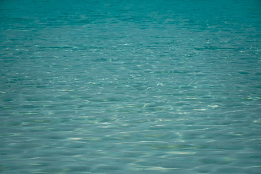 Blue ripped sea water as swimming pool Crystal clear ocean lagoon bay turquoise blue azure water surface closeup natural. close up of water of the ocean with sun shine sparkling.