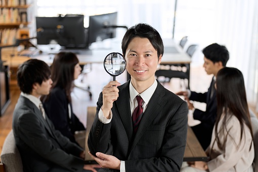 Asian businessman with magnifying glass