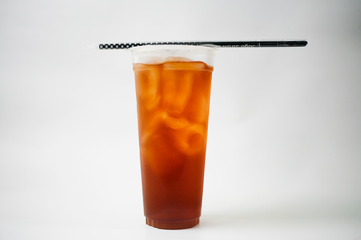 Take away iced tea in plastic cup with straw isolated in white background