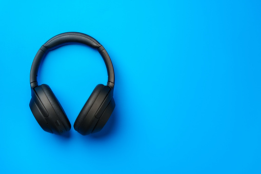 Black headphones on blue background top view photo