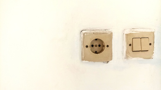 White electric switch and electrical plug socket on a white wall