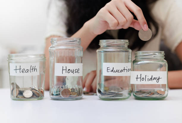 istock A young Asian girl is captured putting coins into a jar, symbolizing her commitment to saving money for both education and future holidays. 1974416959
