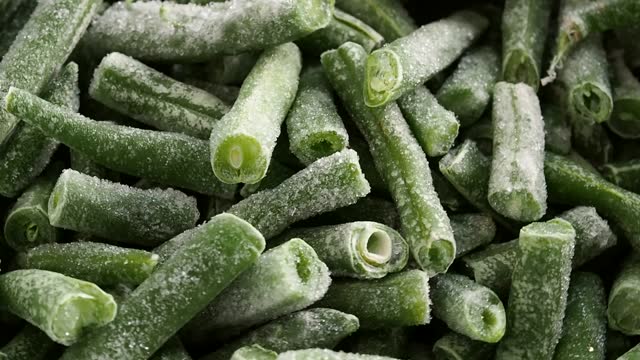 Frozen cut green beans rotating in a circle. Frozen vegetables, healthy food. Close up